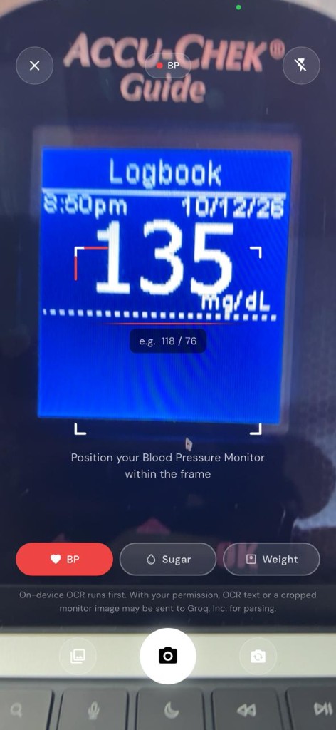 Blood Snap camera view framing an Accu-Chek Guide meter. OCR highlights 135 mg/dL on the logbook screen.